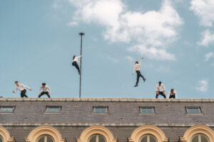 Photographie du spectacle Horizon sur les toits du Palais-Royal à Paris avec des acrobates et circassiens.